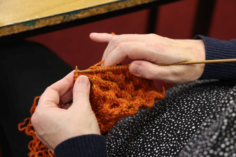 hands using knitting needles and woolen garment